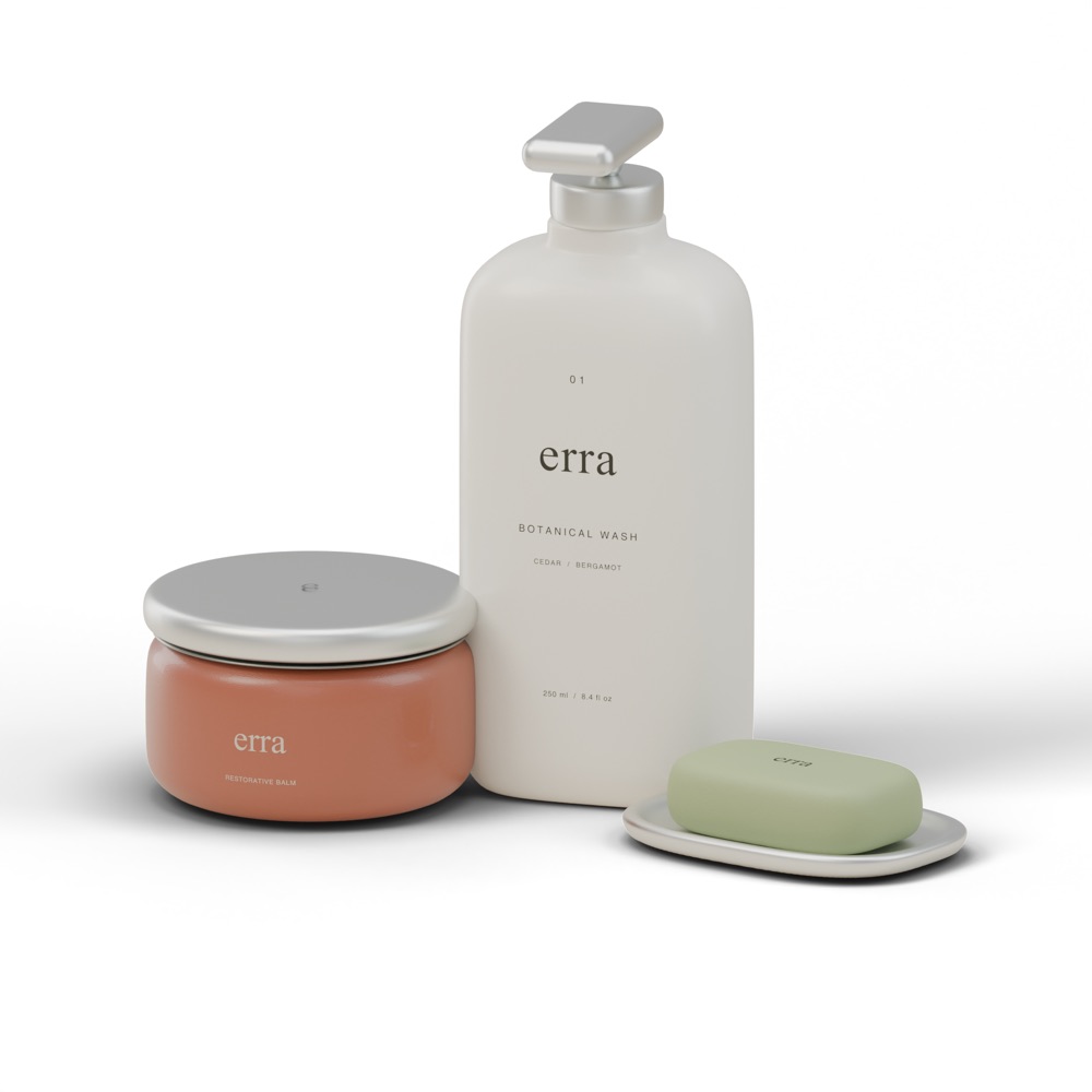 Catalog shot on pure white: a white erra botanical wash pump bottle, a terracotta balm jar with an aluminium lid and a sage soap bar on a metal dish, with soft contact shadows.