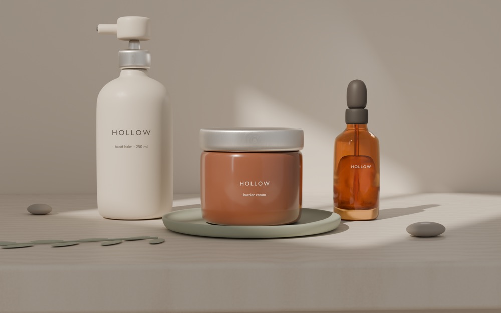Lifestyle scene: a cream Hollow hand balm pump, a terracotta barrier cream jar on a sage dish and an amber dropper bottle on a stone shelf in soft window light.